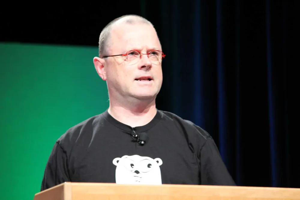 Rob Pike donnant une conférence d'ouverture, debout devant un écran de projection
